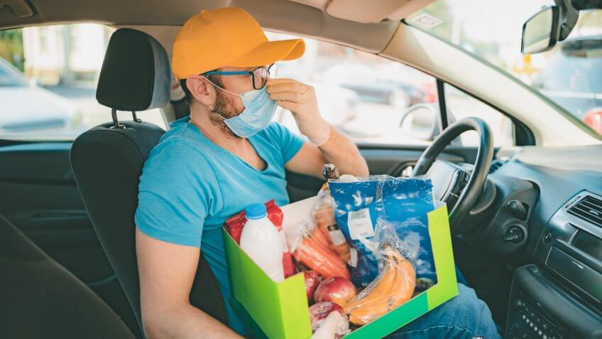 Delivery guy with protective mask and gloves delovering groceries during lockdown and pandemic.