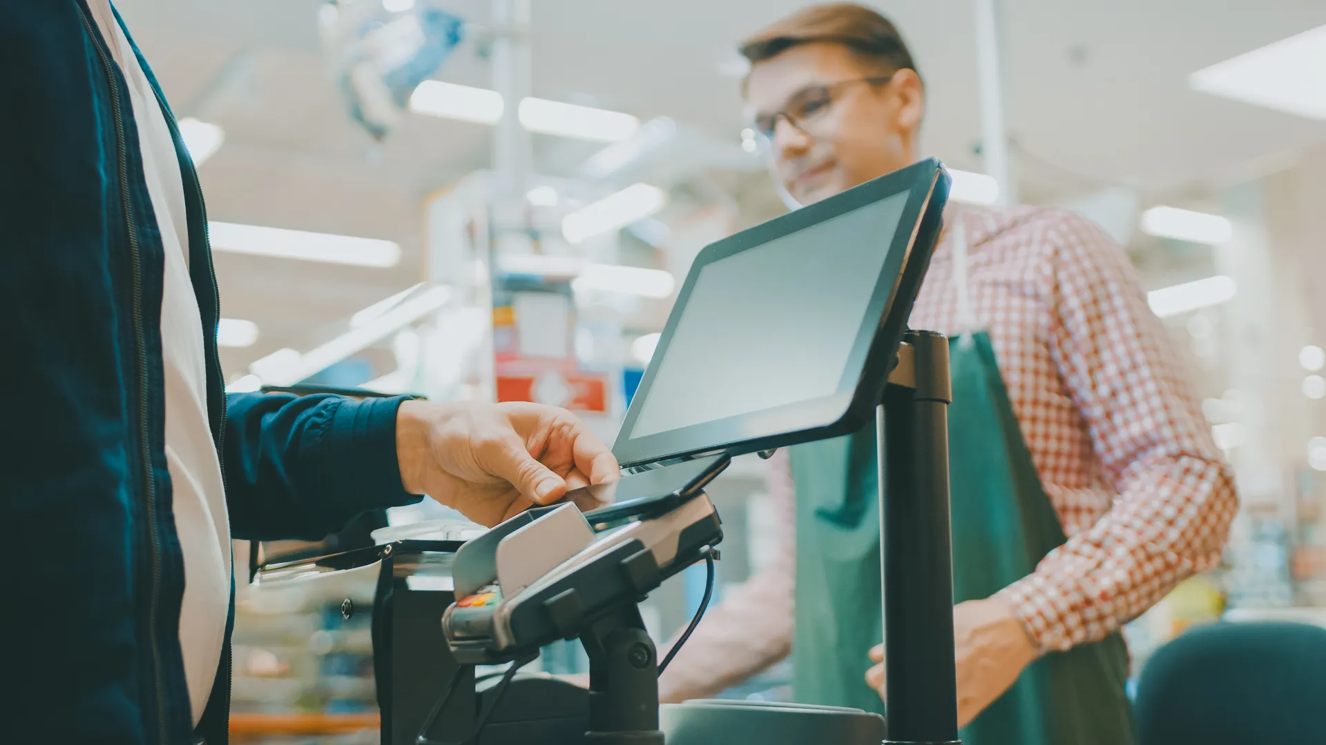 At the Supermarket: Checkout Counter Customer Pays with Smartphone for His Food Items.