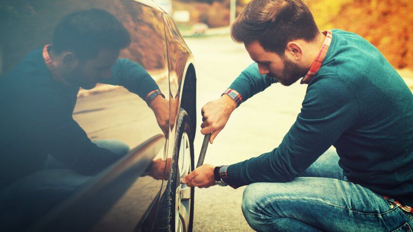 Man changing wheel after a car breakdown at the side of the road.
