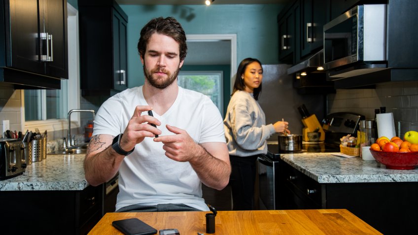A diabetic patient checking his blood sugar using a glaucometer and a wearable smart device.