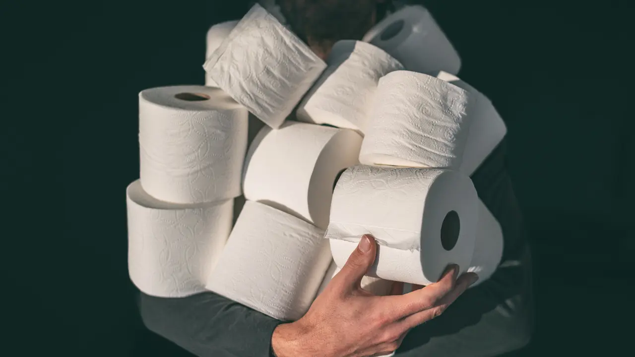 Toilet paper shortage coronavirus panic buying man hoarding carrying many rolls at home in fear of corona virus outbreak closing shopping stores.