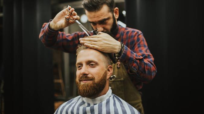 Man at hair salon Hipster young good looking man visiting hairstylist in barber shop.