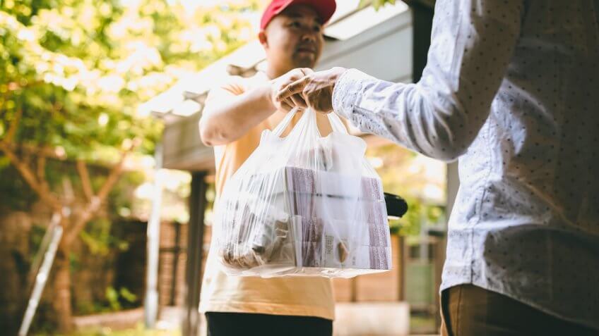 Man Paying For Takeout Food to Delivery Person Using Credit Card Reader.