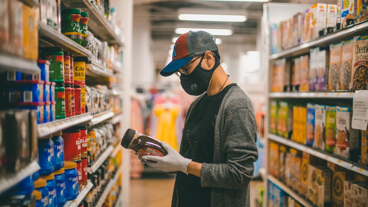 Bethesda, Maryland / USA - April 1, 2020: A man wearing a protective mask and rubber gloves searched for instant coffee at a Target grocery store during the COVID 19 pandemic.