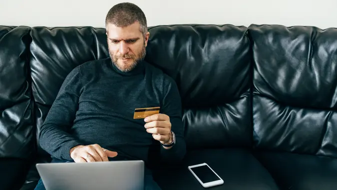 Man at home using credit card for online shopping and payments.