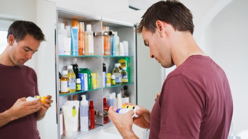 Man looking at bottles from medicine cabinet