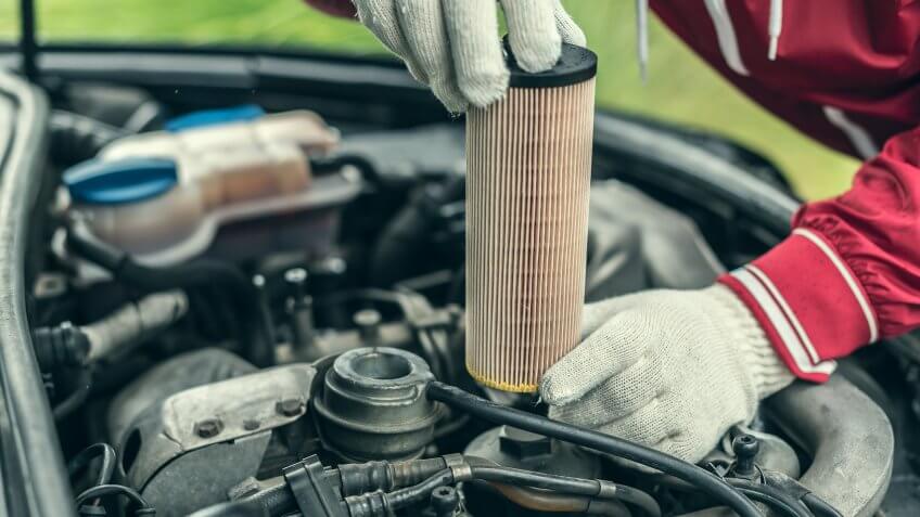 Auto mechanic replaces the car's oil filter.