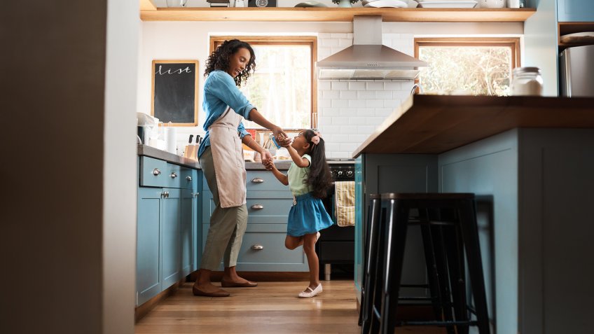 Shot of a young woman dancing with her daughter in the kitchen at home.