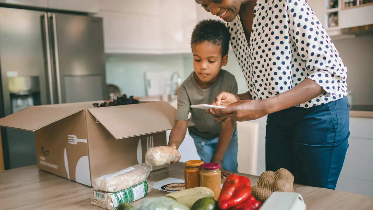 Mother and her son opening parcel with meal kit in their kitchen.