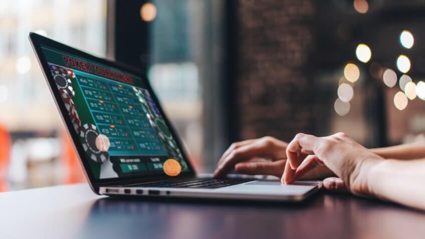 Close up cropped photo of girl hands using her laptop for taking part in online poker tournament.