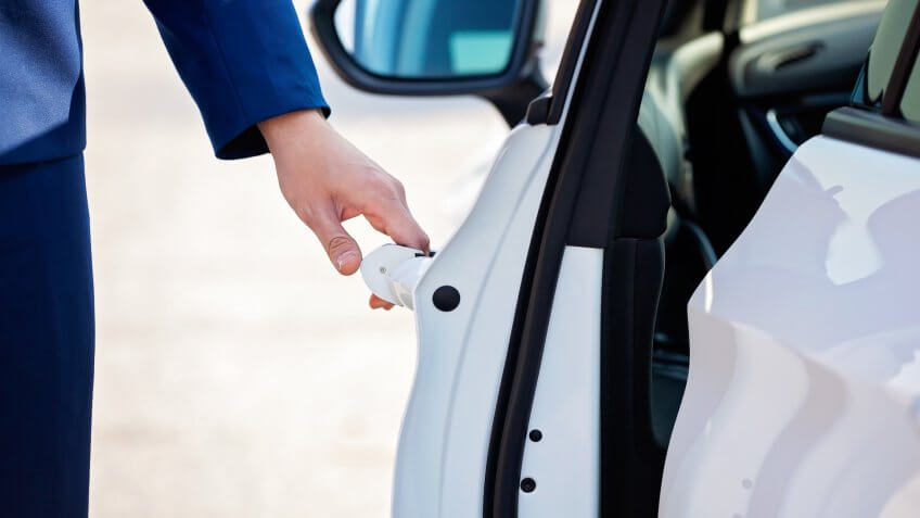 Young businessman opening white car door.