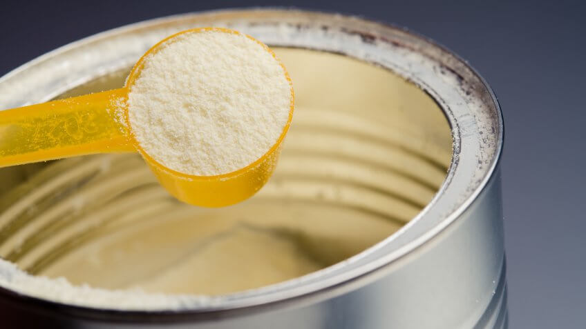 spoon with infant formula on background.