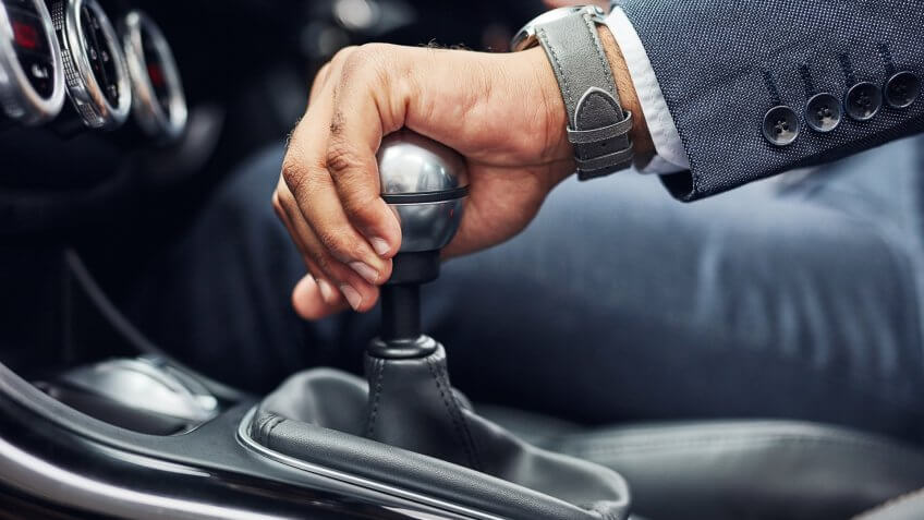 Cropped shot of an unrecognizable man's hand on his gearstick while driving.