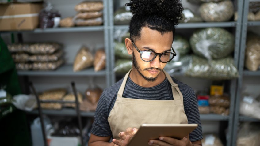 Men using digital tablet in storage room of a natural product shop.