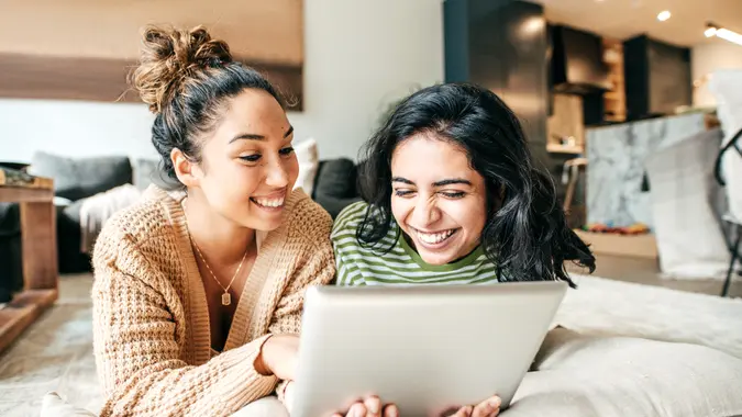 Two female students with digital tablet and cellphone at home.