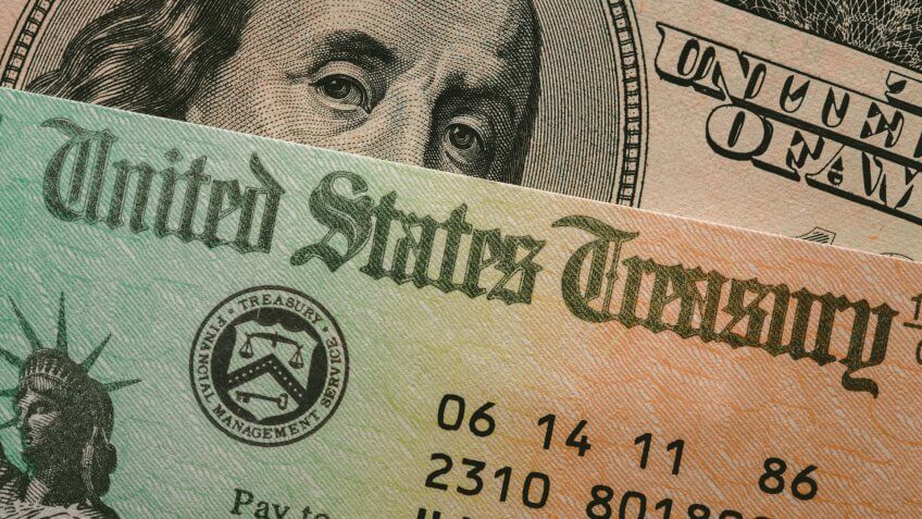 The portrait of Benjamin Franklin on the one hundred dollar bill peering from behind a check issued by the U.