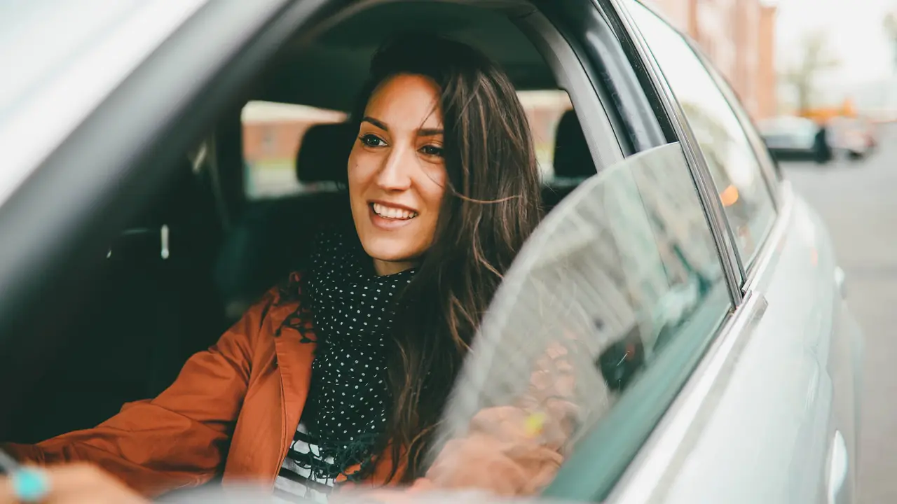 woman driving car smiling.