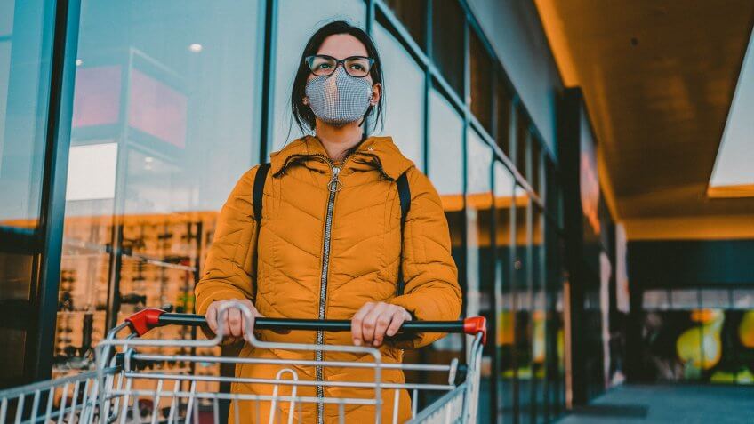 Young beautiful Caucasian woman with shopping cart in grocery store.