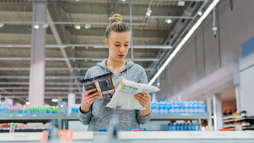 Pregnant Woman buying frozen food and holding a deep-frozen product in a supermarket, I always check the ingredients.
