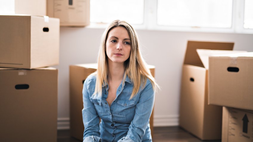 A very sad woman with box at home.