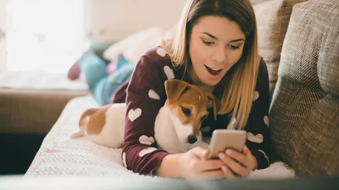 Belle femme à l'aide d'un téléphone portable en position couchée avec son chien.