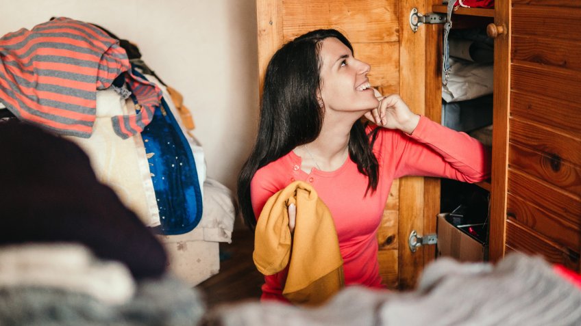 Young woman is sorting out wardrobe.