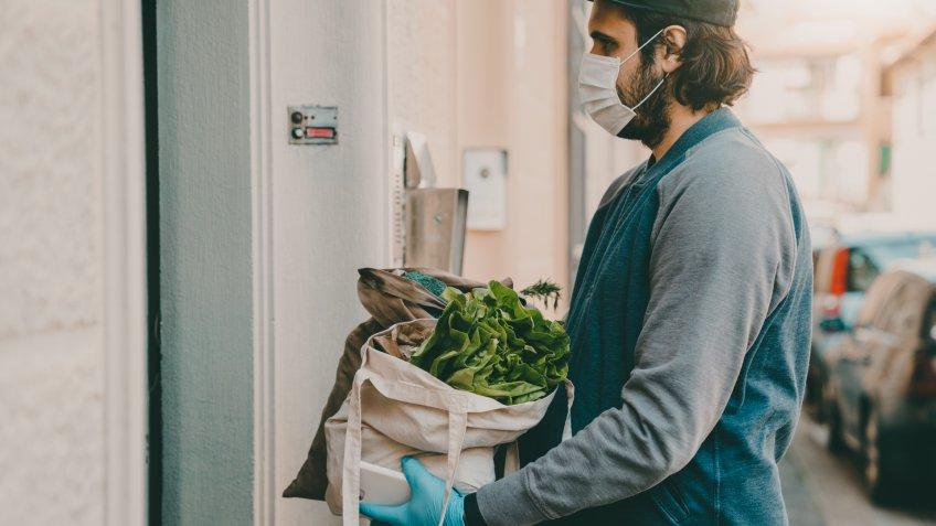 A man is delivering a bag of vegetables and fruit.