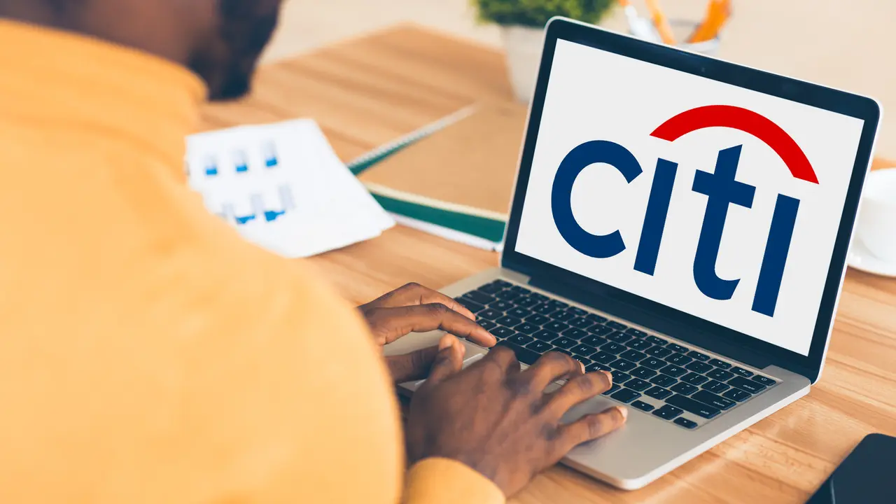 A man working on a laptop displaying the Citi logo, focused and engaged in a modern workspace.