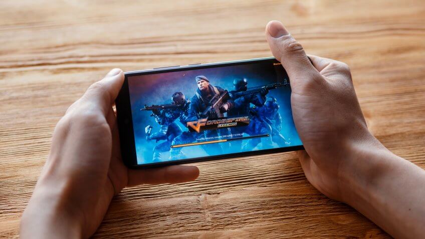 a young guy plays crossfire legendmobile game on the phone.