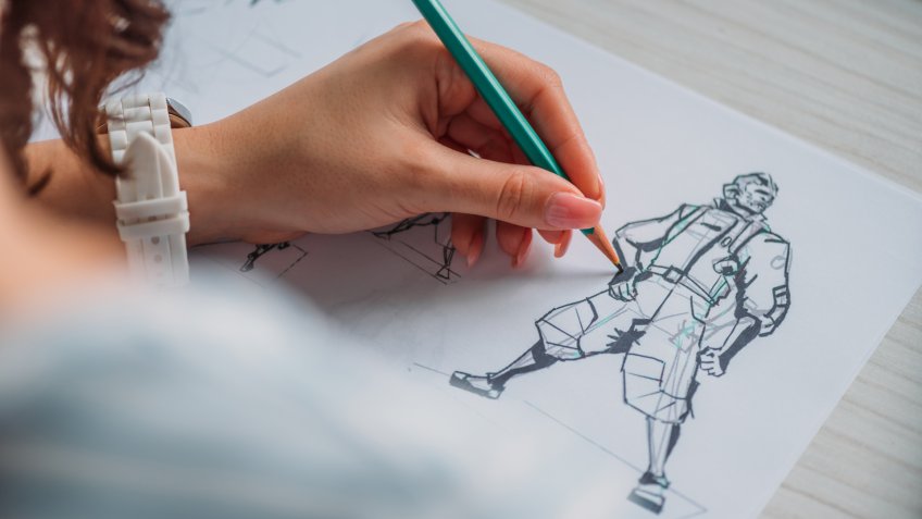selective focus of illustrator drawing cartoon character on paper.