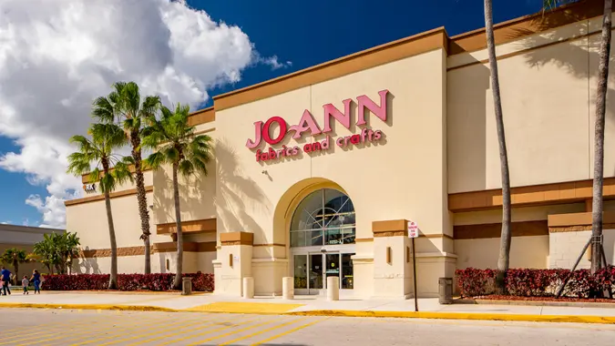 The outisde of a Joann fabric craft store on a sunny day with palm trees in front