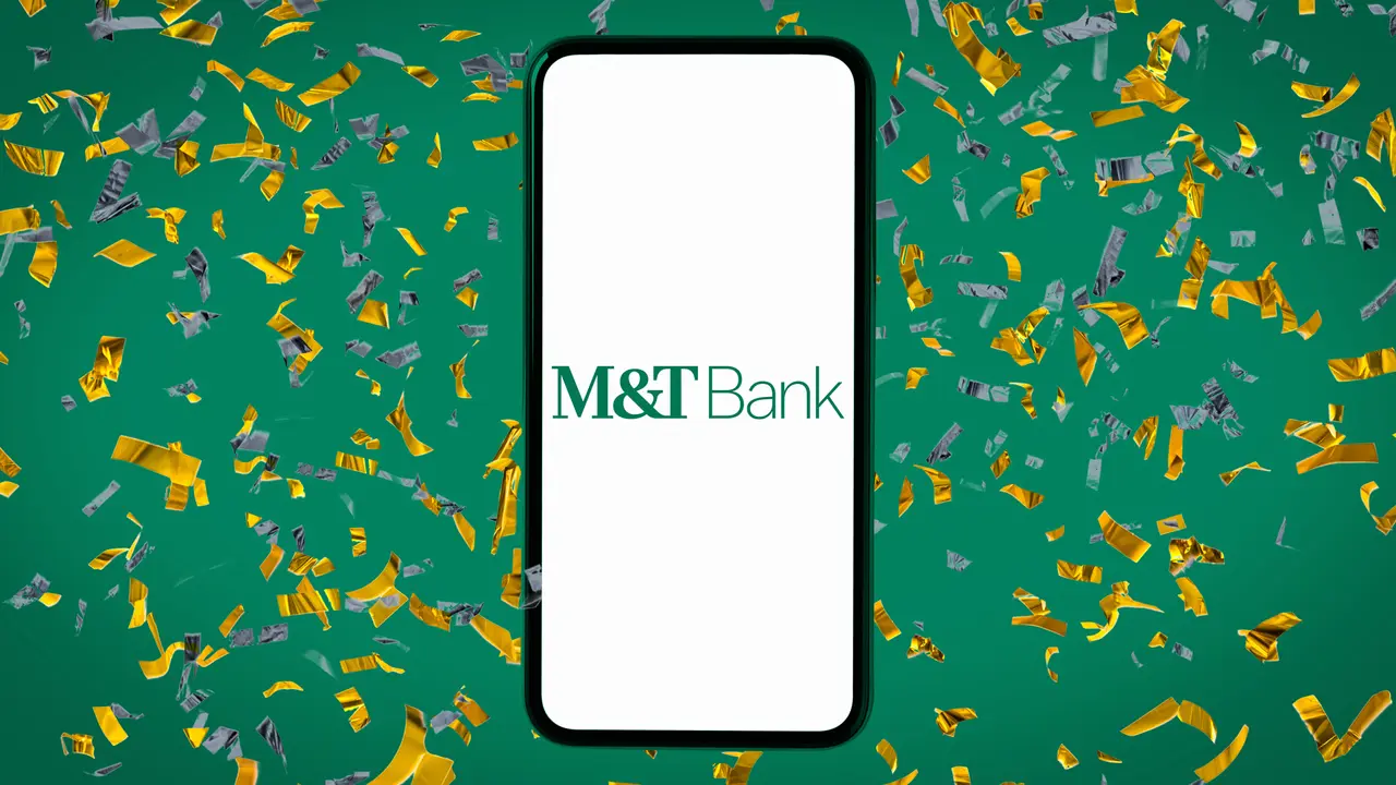 Shot of a smartphone displaying the M&T Bank logo on top of a green background covered with yellow confetti