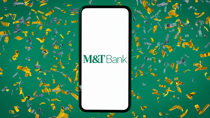 Shot of a smartphone displaying the M&T Bank logo on top of a green background covered with yellow confetti