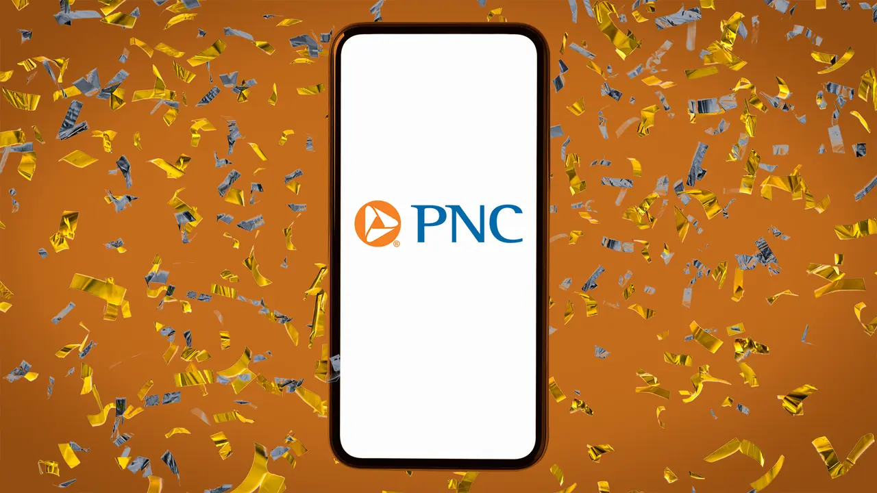 Orange background covered in multi-colored confetti with a smartphone laying on top displaying the PNC Bank logo