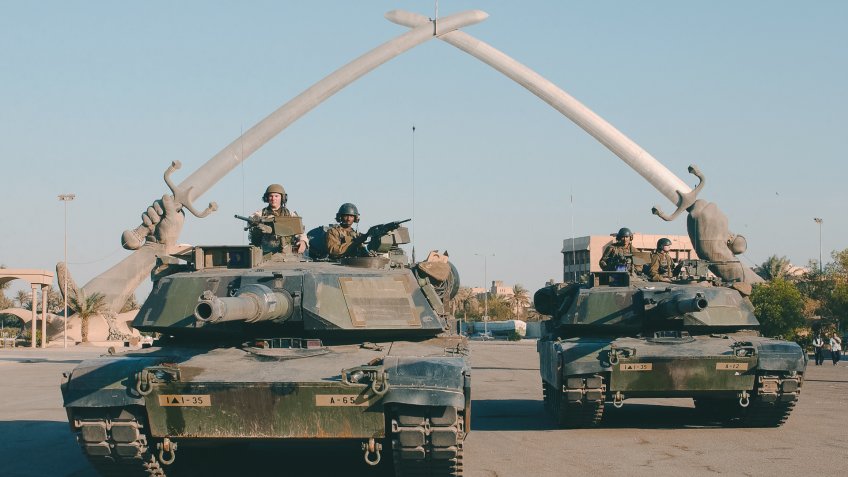 US Army (USA) M1A1 Abrams MBT (Main Battle Tank), and personnel from A Company (CO), Task Force 1st Battalion, 35th Armor Regiment (1-35 Armor), 2nd Brigade Combat Team (BCT), 1st Armored Division (AD), pose for a photo under the "Hands of Victory" in Ceremony Square, Baghdad, Iraq during Operation IRAQI FREEDOM.