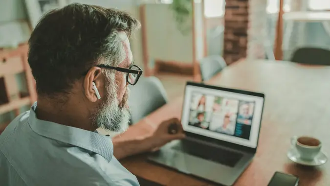 Mature men at home during pandemic isolation have conference call.