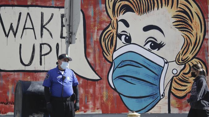 Mandatory Credit: Photo by Marcio Jose Sanchez/AP/Shutterstock (10651138e)Security guard, at left, stands in front of a coronavirus-themed mural, in the arts district of Los AngelesVirus Outbreak California, Los Angeles, United States - 18 May 2020.