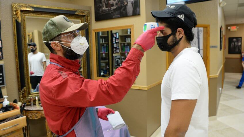 Mandatory Credit: Photo by Larry Marano/Shutterstock (10651183y)Ricky The Barber takes the tempature of a customer priot to cutting his hair at The Man Cave Salon & Spa as Barber Shops, Nail Salons and Restaurants re-open in accordance with Broward County's Phase 1 during the Coronavirus COVID-19 pandemicCoronavirus outbreak reopening, Coral Springs, Florida, USA - 18 May 2020.