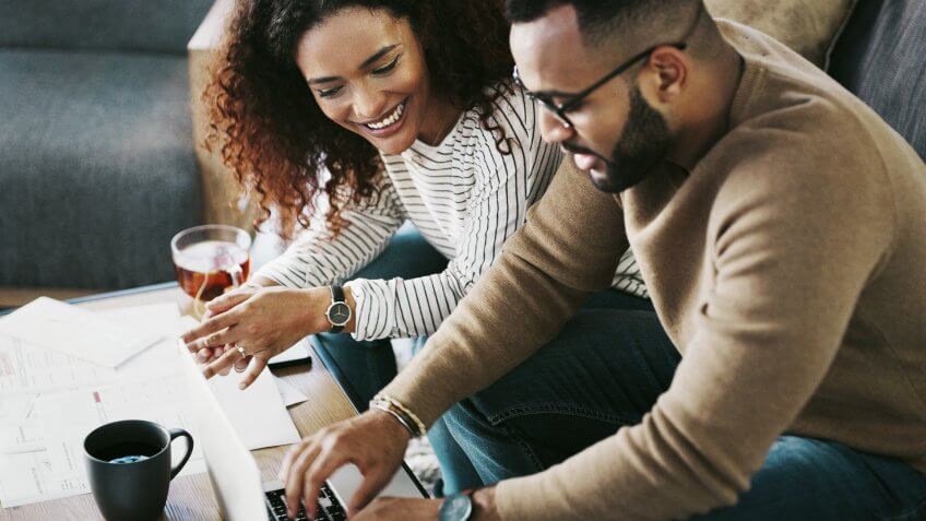 Cropped shot of a young couple using a laptop while going over their finances at home.