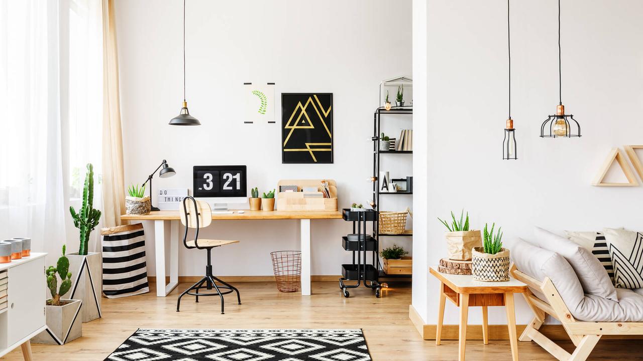 Black and white geometric carpet in multifuncional workspace with painting on wall above desk.