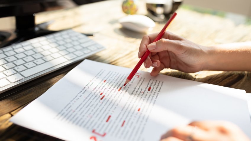 Close-up Of A Person's Hand Marking Error With Red Marker On Document.