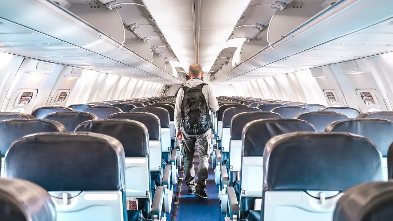 Inside view of commercial airplane with lonely man traveler - Emergency travel concept about flight cancellation - Aerospace industry crisis with empty plane on bright azure filter.