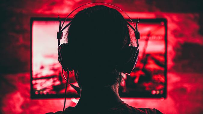 Woman wearing headphones playing video games late at night.