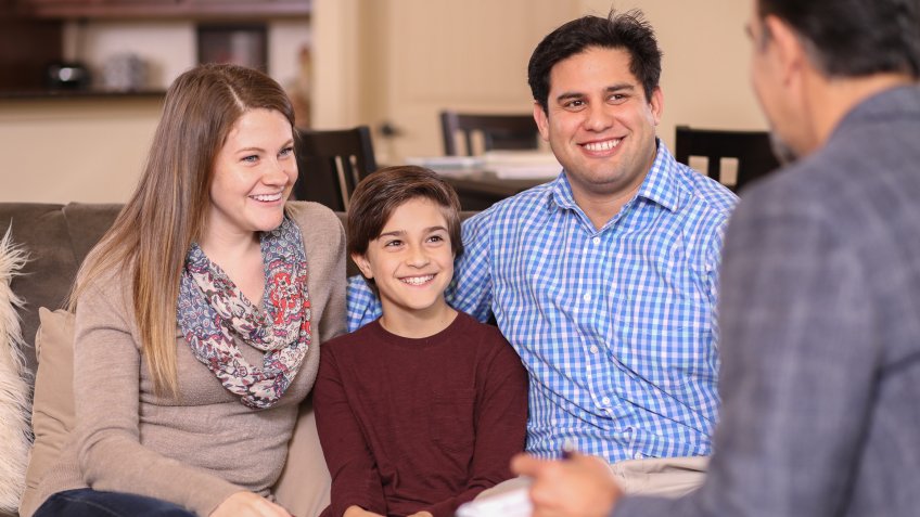 Multi-ethnic family at home with mental health professional, social worker, or family therapist.