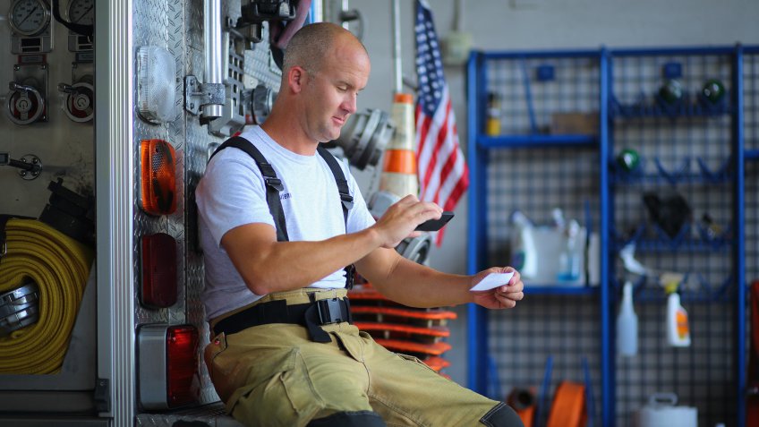 Fireman depositing check with mobile phone at the fire station.