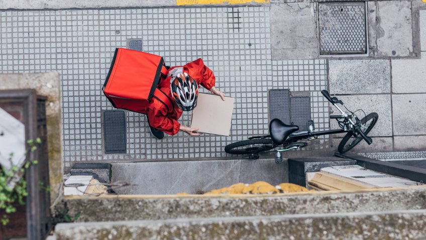 One man, delivery guy in city, delivering pizza in city, holding pizza box.