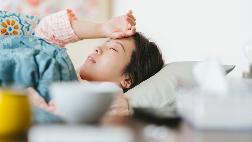 A women is feeling sick and sleeping on a sofa at home.