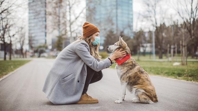Woman during pandemic isolation walking with her dog in park.