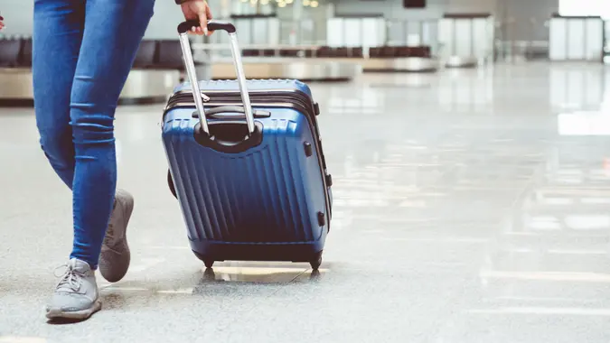 Woman in international airport walking with luggage.