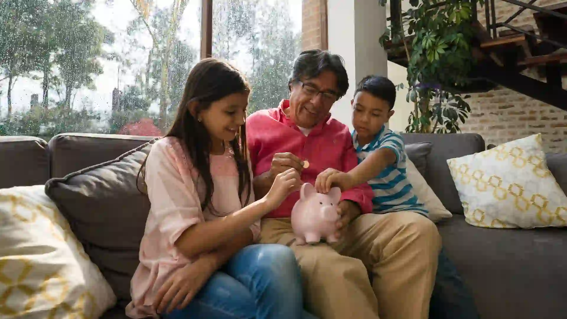 Picture of a two kids and a dad gathering around a piggy bank and learning about saving money